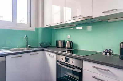 a kitchen with white cabinets and green walls at Plaka Central in Athens