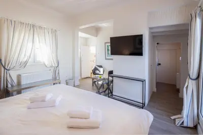 a white bedroom with a bed and a flat screen tv at Downtown Cocoon with Roof Deck in Athens