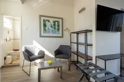a living room with two chairs and a tv at Downtown Cocoon with Roof Deck in Athens