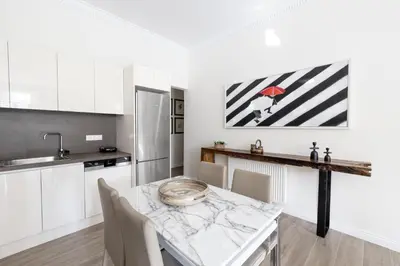 a kitchen with a dining room table with white cabinets at Historic Plaka's Deluxe Apartment in Athens