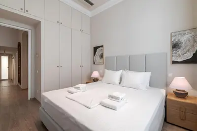 a white bedroom with a large white bed with two lamps at Historic Plaka's Deluxe Apartment in Athens