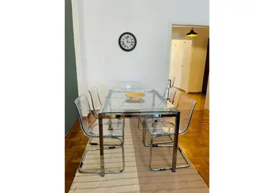 a glass table with four chairs and a clock on the wall at Cozy Apartment in Central Athens - Sleeps 6 in Athens
