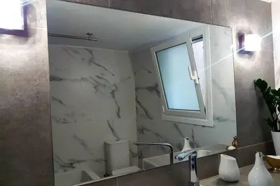 a bathroom mirror with a sink and a window at Dream apartment in Athens