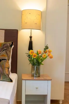 a vase of flowers on a table next to a bed at IPELHOME - Plaka Boutique Apartments in Athens