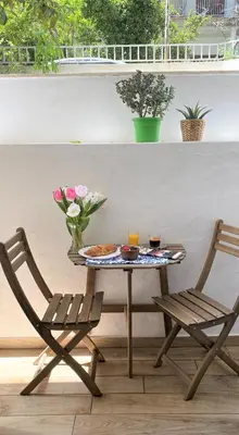 a table and two chairs sitting next to a table with flowers at The Countess Riencourt Apartment in Athens