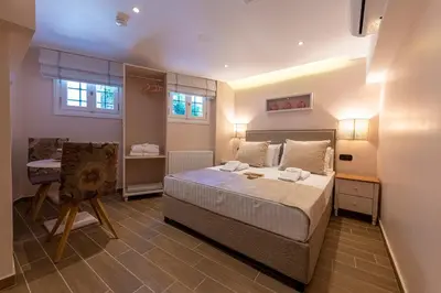 a bedroom with a bed and a table and two windows at IPELHOME - Rodi Boutique Apartment in Athens