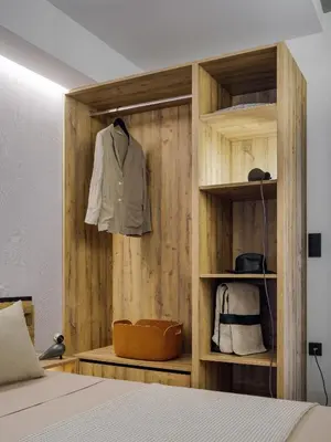 a bedroom with a wooden wall with a suit on a shelf at 3 Olive Trees in Anavissos