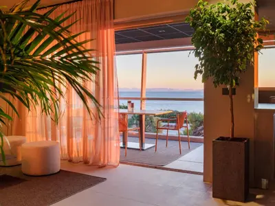 a living room with a table and a view of the ocean at 3 Olive Trees in Anavissos