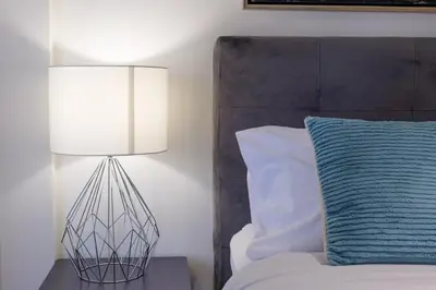 a lamp sitting on a table next to a bed at Faliro Lux Apartment By The Sea VIPGreece in Athens