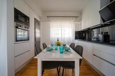 a white kitchen with a white table and chairs at Faliro Lux Apartment By The Sea VIPGreece in Athens