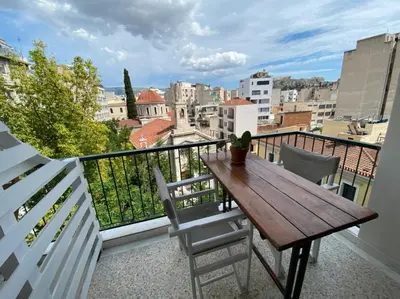 a balcony with a wooden table and chairs at Mosaics aprtm in Monastiraki with Acropolis view in Athens