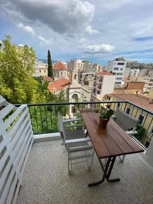a balcony with a wooden table and chairs at Mosaics aprtm in Monastiraki with Acropolis view in Athens