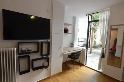 a living room with a desk and a television on a wall at Studio Mavili in Athens