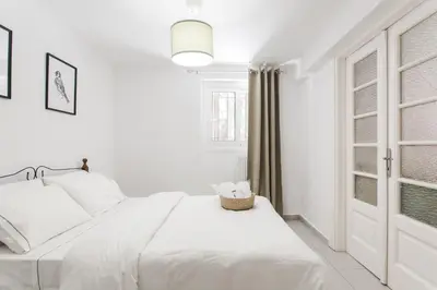 a white bedroom with a bed and a window at Plaka's Hyatt in Athens