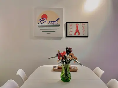 a white table with a vase with flowers on it at Becool Apartment in Porto Rafti