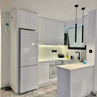 a white kitchen with white cabinets and a refrigerator at Becool Apartment in Porto Rafti