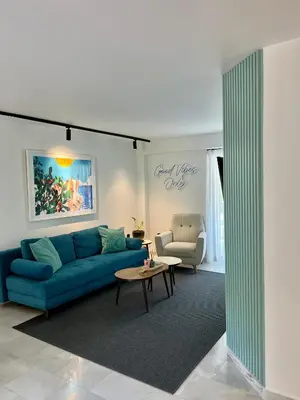 a living room with a blue couch and a table at Becool Apartment in Porto Rafti