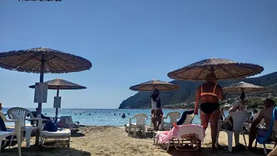 a group of people on a beach with umbrellas at Luxurious apartment close to the beach and airport in Porto Rafti