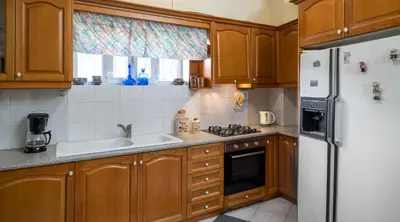a kitchen with wooden cabinets and a white refrigerator at ViLLA127 in Athens