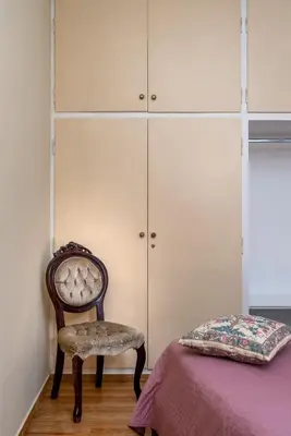a bedroom with a chair and a bed and cabinets at ViLLA127 in Athens