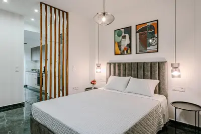 a bedroom with a white bed and a kitchen at Place to be Athens apartment in Athens