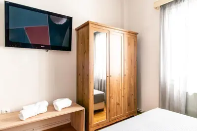 a bedroom with a wooden cabinet and a tv on a wall at Place to be Athens apartment in Athens