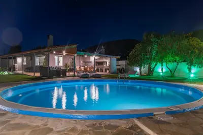 a swimming pool in front of a house at night at Cuervo Poolside Villa in Kalívia Thorikoú