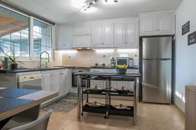 a kitchen with white cabinets and a stainless steel refrigerator at Cuervo Poolside Villa in Kalívia Thorikoú