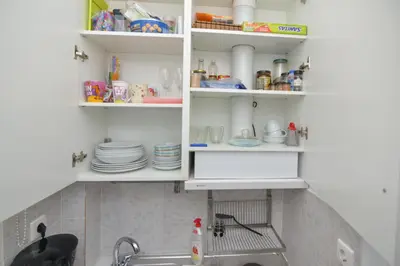 a kitchen with a sink and white cabinets with dishes at Athens Stylish studio in front of Syntagma metro stop for 2 in Athens
