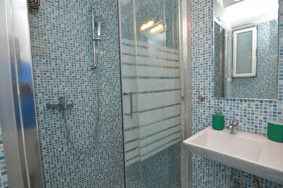 a blue tiled bathroom with a shower and a sink at Athens Stylish studio in front of Syntagma metro stop for 2 in Athens