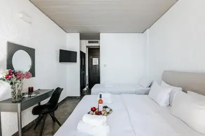 a white living room with a white bed and a table at Apollo Resort in Agia Marina Aegina