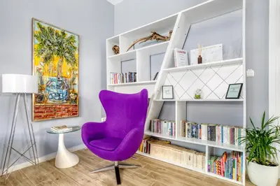 a purple chair in a room with bookshelves at Spacious flat with courtyard in Peristeri! in Athens