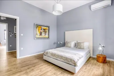 a white bedroom with a bed and a wooden floor at Spacious flat with courtyard in Peristeri! in Athens