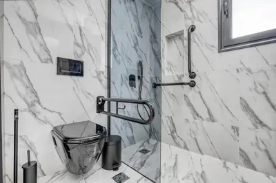 a bathroom with white marble walls and a shower at Spacious flat with courtyard in Peristeri! in Athens