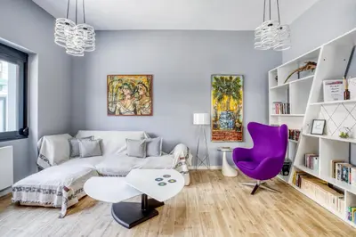 a living room with a bed and a purple chair at Spacious flat with courtyard in Peristeri! in Athens