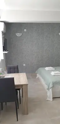 a bedroom with a bed and a wooden table at AVR Airport Deluxe Suites 6 AIRPORT FREE SHUTLE in Markopoulo