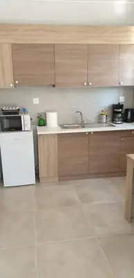 a kitchen with wooden cabinets and a white refrigerator at AVR Airport Deluxe Suites 6 AIRPORT FREE SHUTLE in Markopoulo