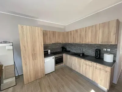 a kitchen with wooden cabinets and a white appliance at AVR Airport Deluxe Suites 6 AIRPORT FREE SHUTLE in Markopoulo