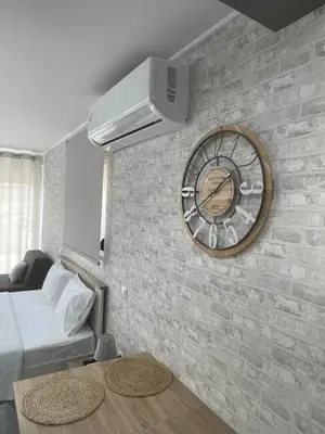 a clock on a brick wall in a bedroom at AVR Airport Deluxe Suites 6 AIRPORT FREE SHUTLE in Markopoulo