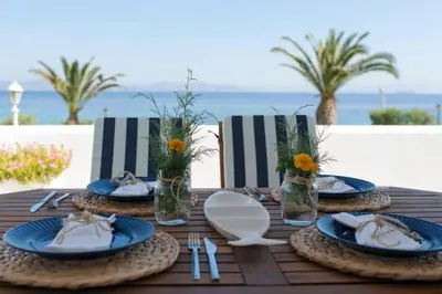 a wooden table with blue plates and utensils on it at Palmaya Villa, unique seafront experience in Vaia