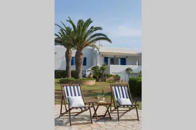 a group of chairs and a table in front of a house at Palmaya Villa, unique seafront experience in Vaia