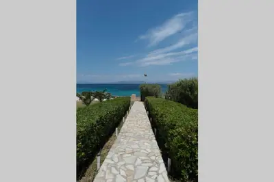 a walkway through a hedge with the ocean in the background at Palmaya Villa, unique seafront experience in Vaia