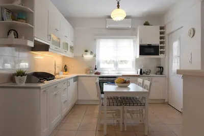 a kitchen with white cabinets and a table with chairs at Palmaya Villa, unique seafront experience in Vaia
