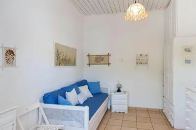 a living room with a blue couch and a chandelier at Palmaya Villa, unique seafront experience in Vaia