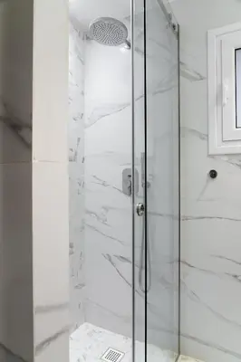 a shower with a glass door in a bathroom at Glyfada Gallery Apartment by First Class Properties in Athens