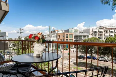 a table with a vase of flowers on a balcony at Glyfada Gallery Apartment by First Class Properties in Athens