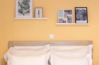a bedroom with yellow walls and a bed with white pillows at Acropolis Sweet House 3 in Athens