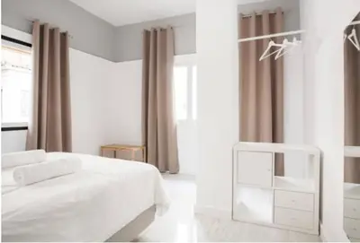 a white bedroom with a white bed and a window at Dion Suites in Athens