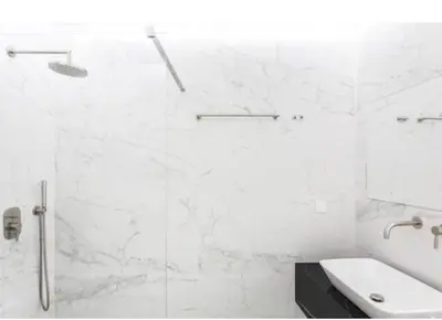 a white bathroom with a shower and a sink at Dion Suites in Athens