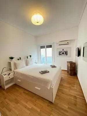 a white bedroom with a large bed and a window at Olympic Hadrian Apartment next to Acropolis in Athens